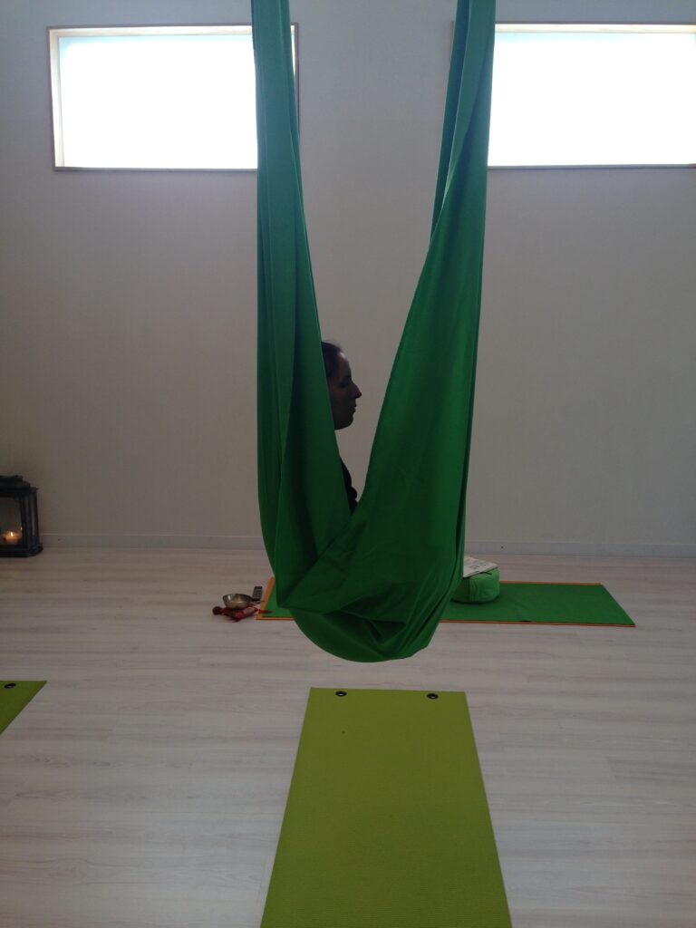 Foto van Debby die met haar benen omhoog zit in een aerial yoga doek.