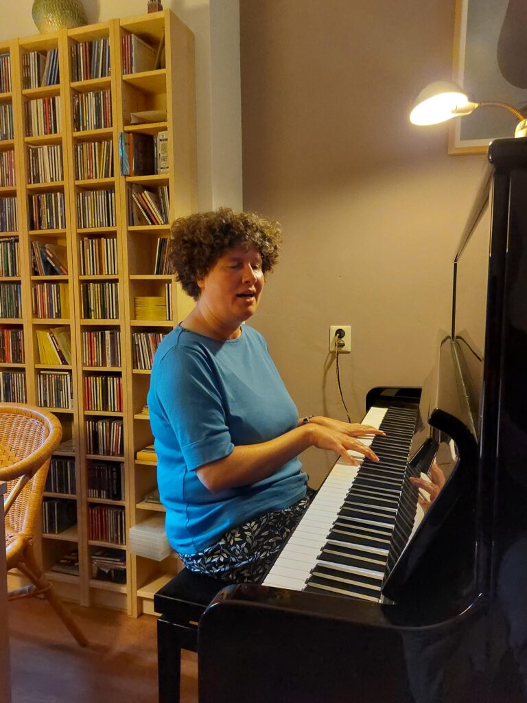 Foto van Hedda Schueler die zingend aan de piano zit.