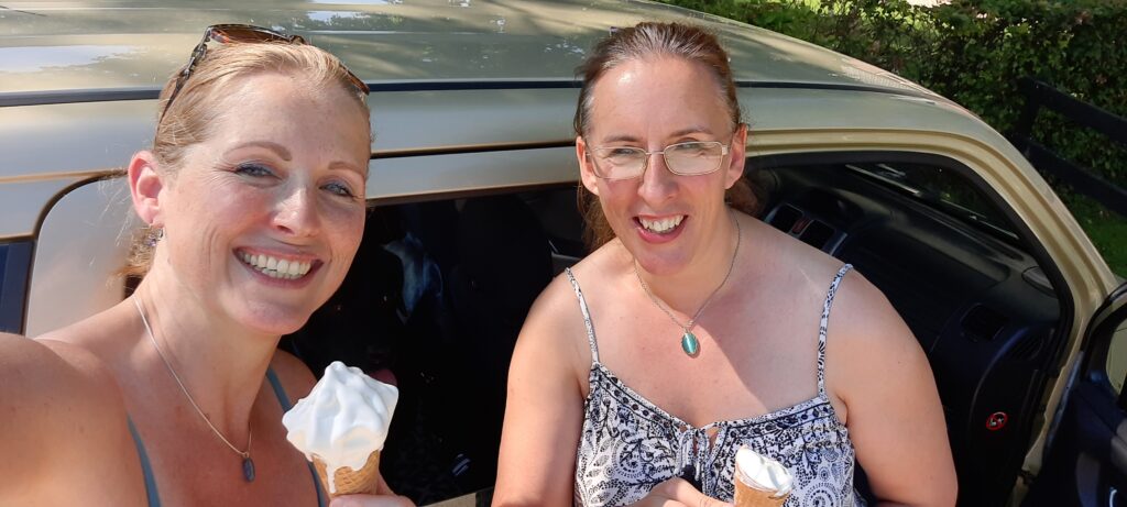 Aletta en Debby staan naast de auto met een ijsje in hun hand.