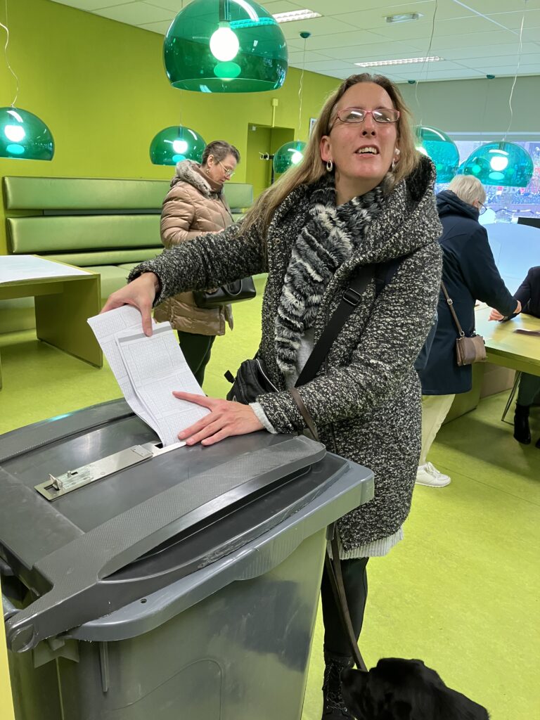 Foto van Debby die tijdens de Tweede Kamerverkiezingen in 2023 haar stembiljet in een stembus gooit.