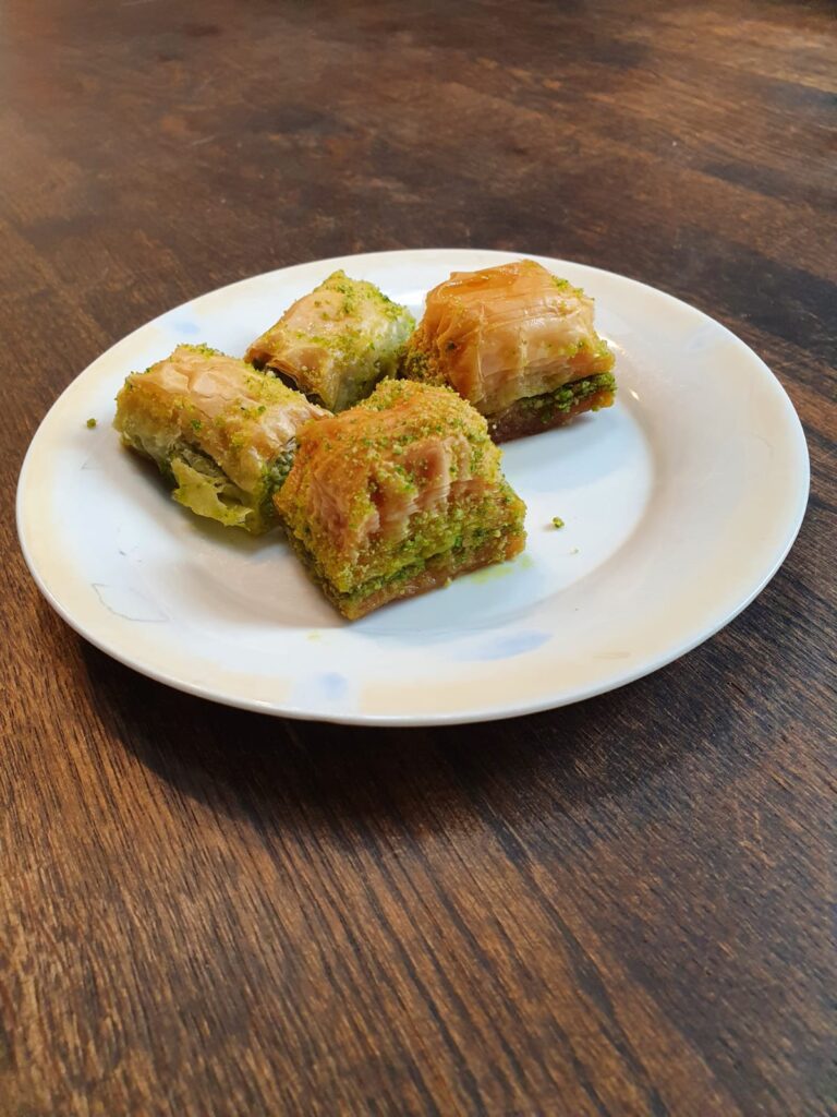 Foto van vier stukjes baklava op een wit bord.